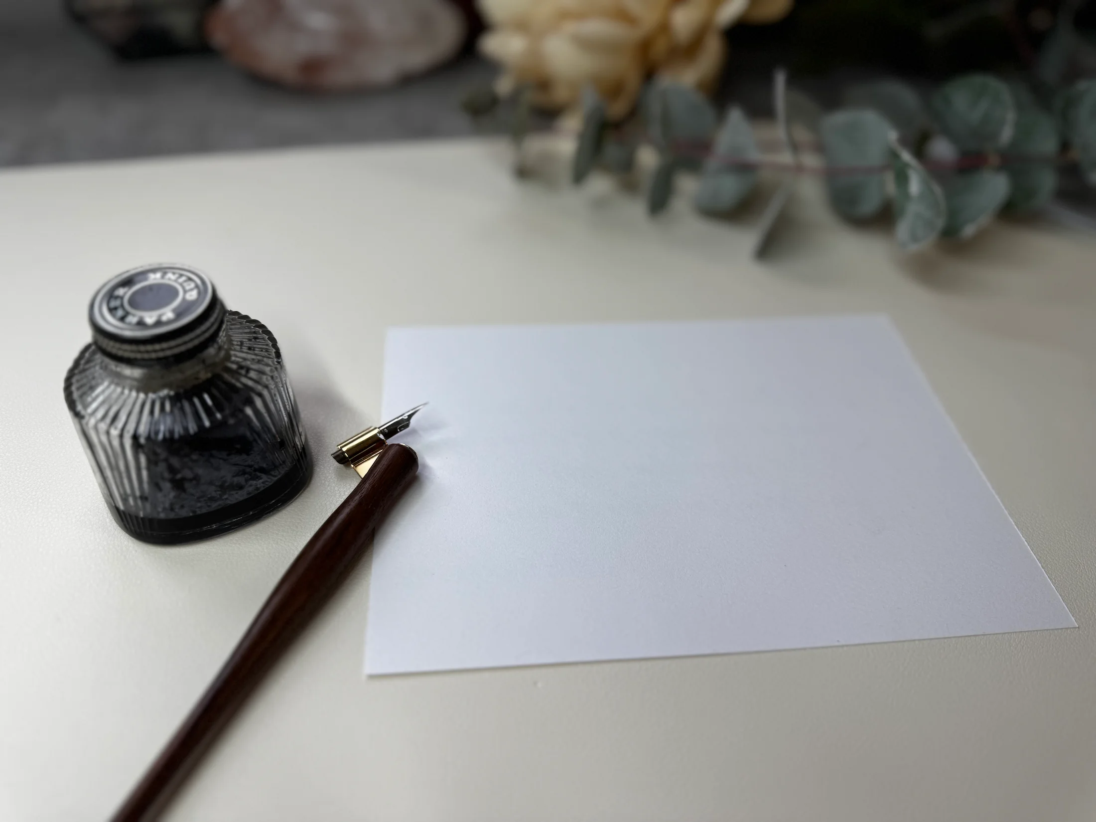 Blank card beside a calligraphy ink bottle and pen