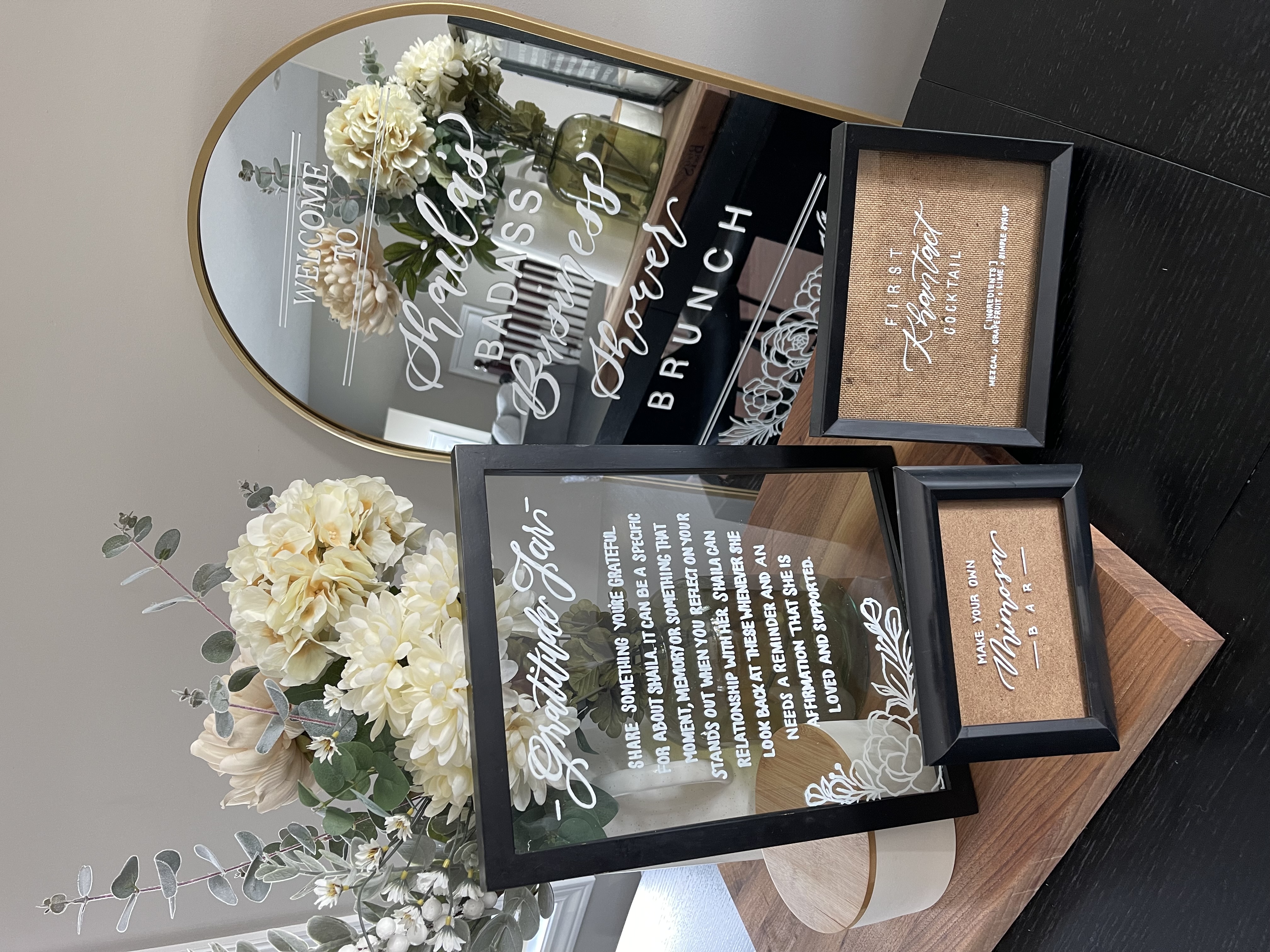 Layered event signage with white calligraphy and floral styling
